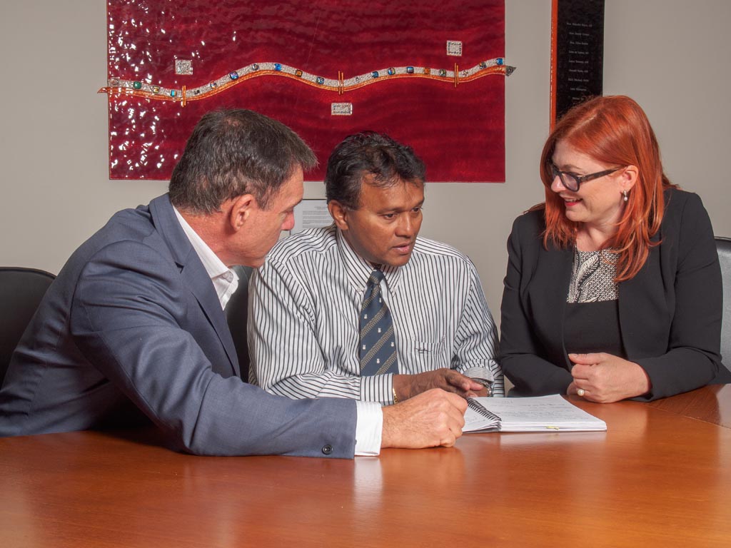Tanya sitting with two working professionals in a board room. The image is aimed to envision the culture workshops that RedHead Communications provide.